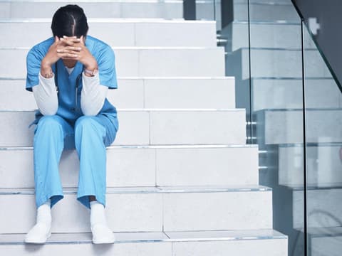 Ausgebrannte Ärztin sitzt auf Krankenhausstufen