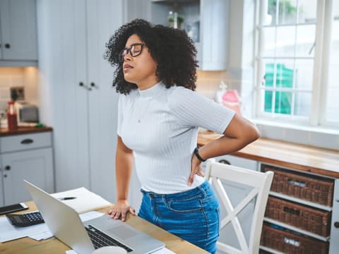 Frau hat Rückenschmerzen im Homeoffice