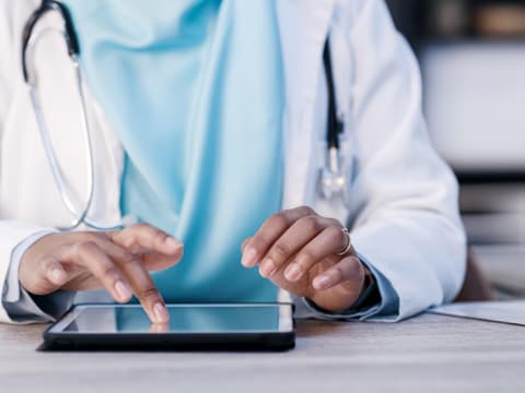 Ärztin nutzt Tablet zur Patientendatenübertragung
