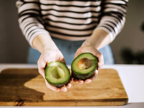 Frau hält Avocado in der Hand