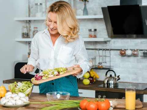 Frau schneidet Salat selbst