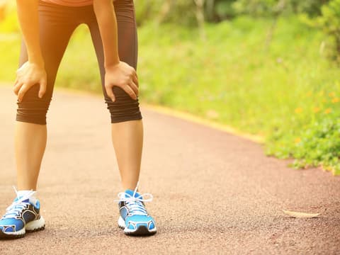Joggerin stützt sich auf Knien ab