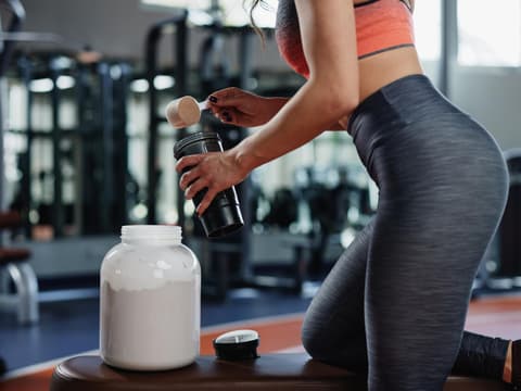 Frau im Fitnessstudio mischt sich Proteindrink