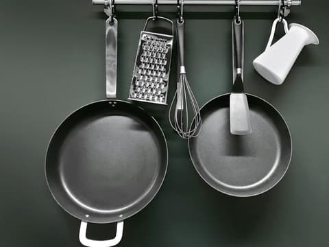 Pfannen und Töpfe an Küchenwand