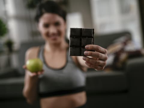 Frau beim Sport isst Schokolade