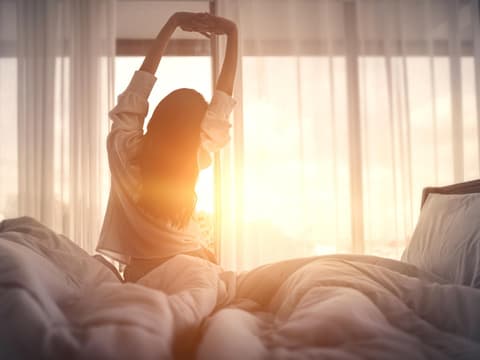 Frau steht aus dem Bett auf