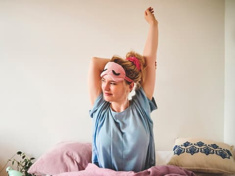 Frau streckt sich im Bett