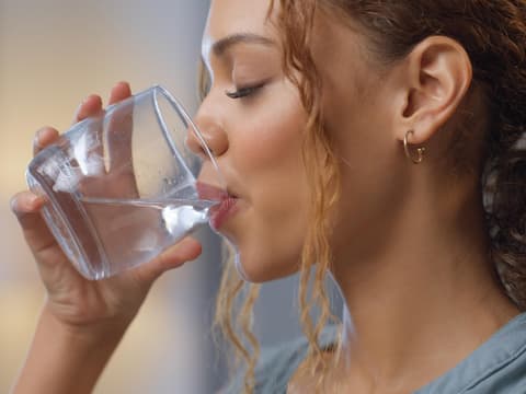 Frau trinkt Wasserglas.