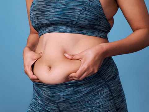 Frau in Sportsachen hält sich Bauch