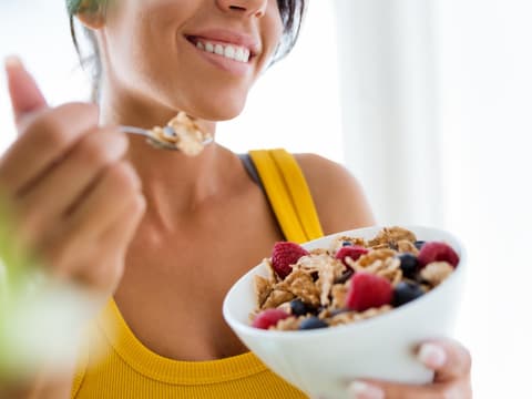 Lachende Frau isst Müsli