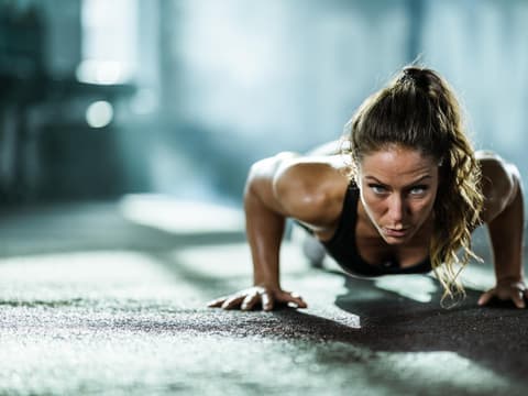 Sportliche Frau macht Liegestütz ud guckt in die Kamera