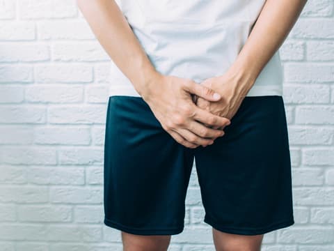 Mann hält seine Hände vor den Intimbereich