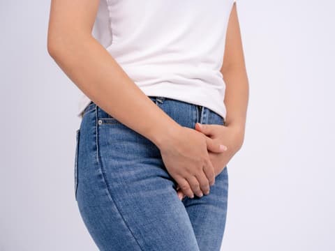 Frau hält ihre Hände vor den Intimbereich