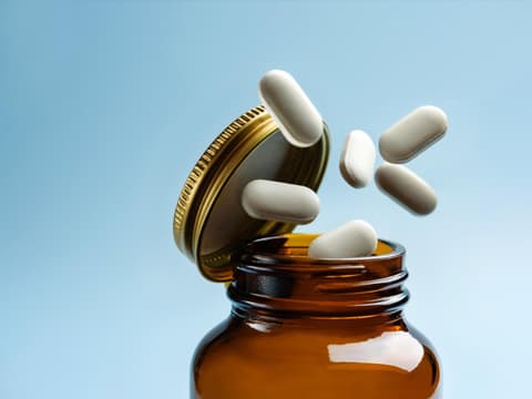 Tabletten fallen aus einer Glasflasche