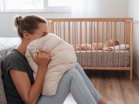 Depressive Mutter, die vor Verzweiflung im Kissen schreit