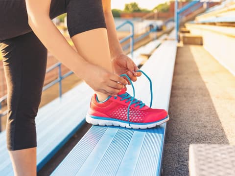 Frau auf Treppe bindet sich Sportschuhe zu