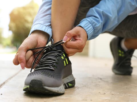 Frau bindet sich Sportschuhe zu