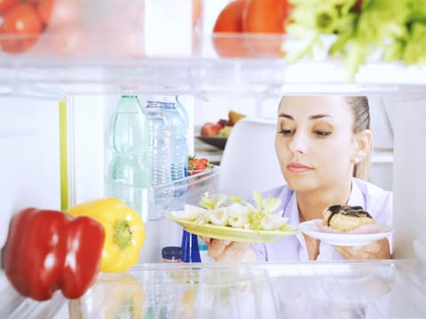 Frau guckt in den Kühlschrank