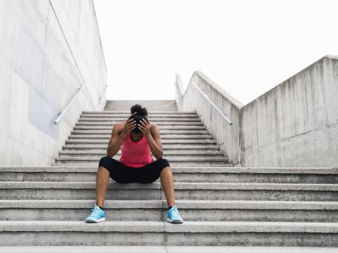 Joggerin sitzt mit Schwindel auf Treppe