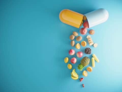 Früchte und Obst fallen aus einer Vitaminkapsel heraus
