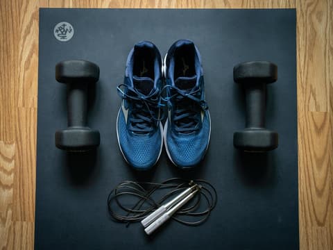 Sportschuhe und Hanteln auf Yoga-Matte