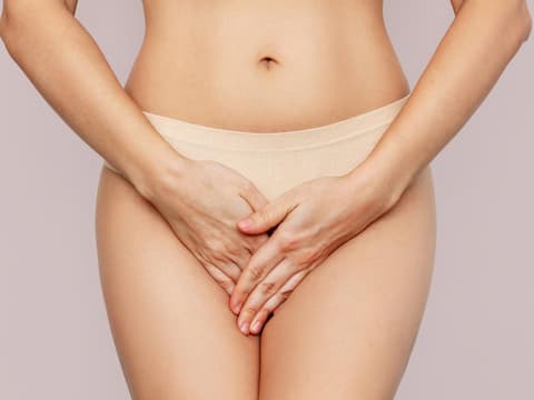 Frau hält die Hände vor ihren Intimbereich