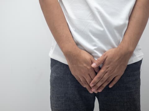 Mann hält sich die Hände vor den Intimbereich