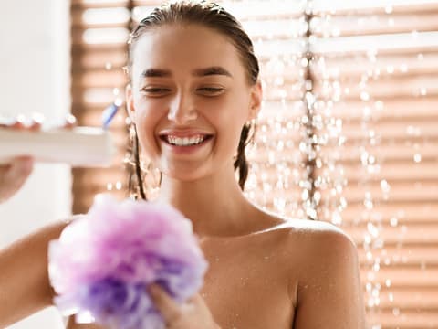 Frau mit Duschschwamm in Dusche