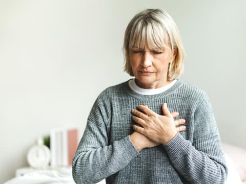 Frau fasst sich ans Herz