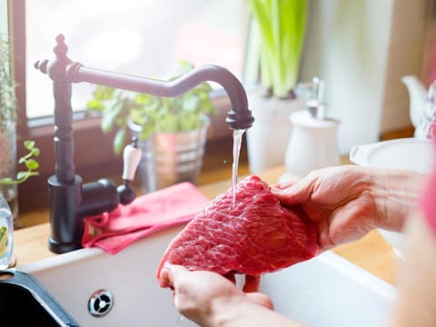 Mann wäscht rohes Steak
