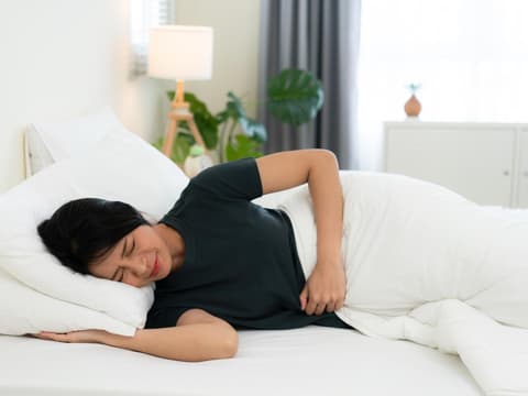 Frau im Bett mit Schmerzen