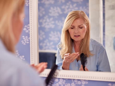 Frau mit Haarausfall im Herbst untersucht Bürste