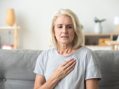 Frau fasst sich an die Brust