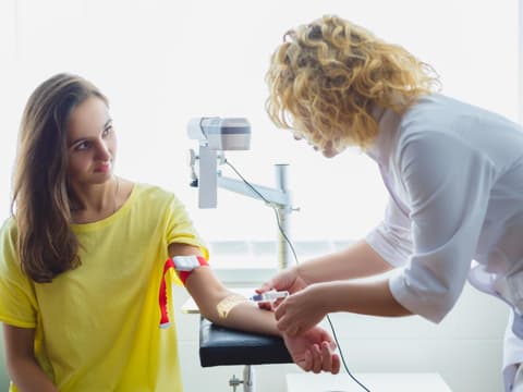 Frau wird Blut abgenommen