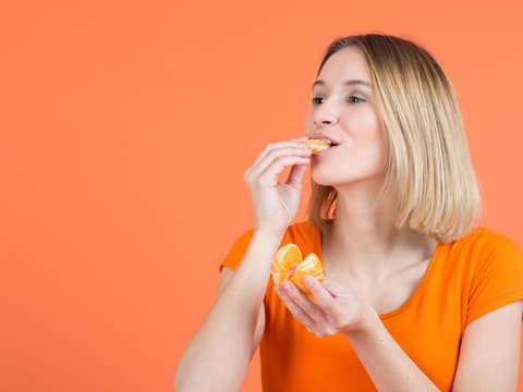Frau beißt in Mandarine