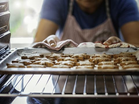 Frau holt Manuka-Plätzchen aus dem Ofen