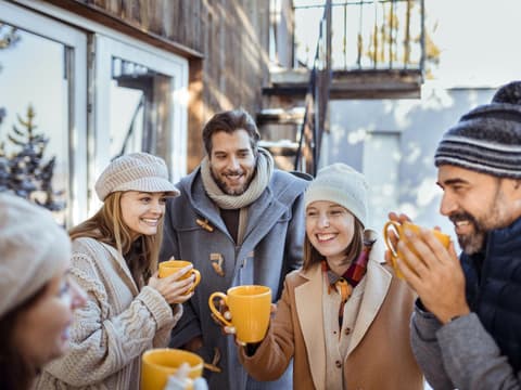 Menschen stehen draußen und trinken gemeinsam Glühwein