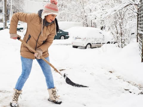 Frau schippt Schnee