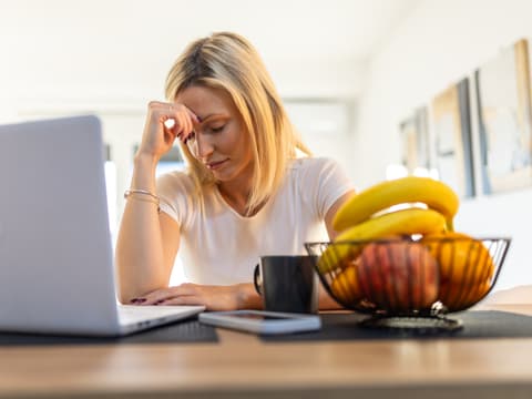 Frau sitzt am Laptop und ist erschöpft