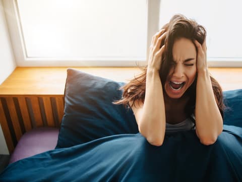 Psychisch kranke Frau liegt im Bett und leidet unter Wahnvorstellungen 