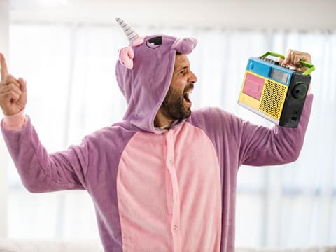 Verspielter Mann im Einhornkostüm singt mit Radiomusik