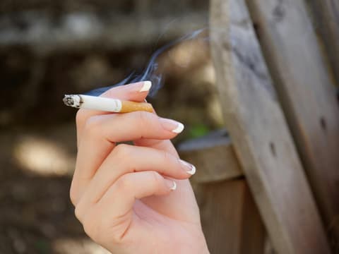 Frau hält Zigarette in den Fingern