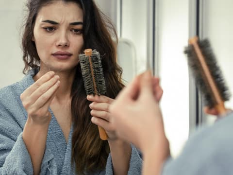 Frau fischt Haare aus einer Rundbürste