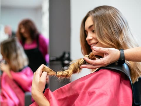 Frau sitzt beim Friseur, um ihre Haare zu spenden
