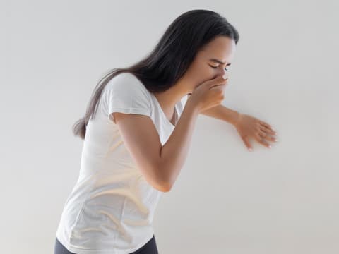 Frau ist übel und sie hält sich die Hand vor den Mund