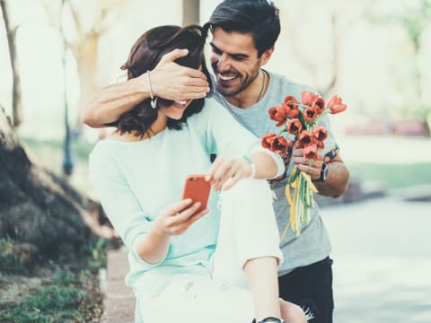 Mann überrascht Frau mit Blumen