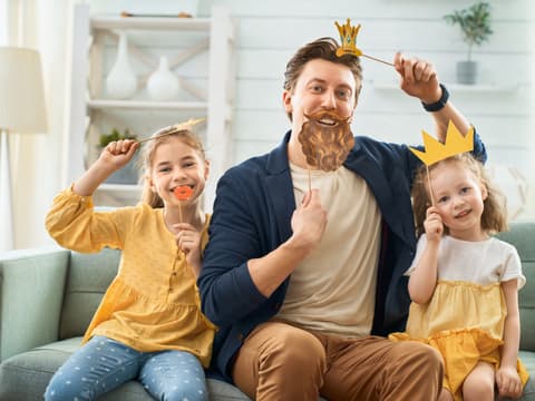 Ein Vater spielt mit seinen Kindern, sie tragen Masken