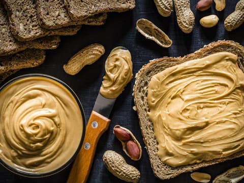 Cremige Nussbutter im Schälchen und auf einem Vollkorntoast