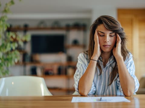 gestresste Frau im Büro massiert sich mit geschlossenen Augen die Schläfen