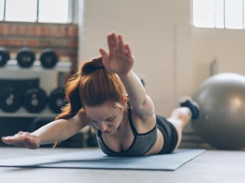 Frau macht Superman-Übung im Fitnessstudio